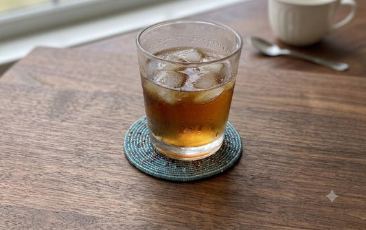 Glass on blue beaded coaster on wooden table