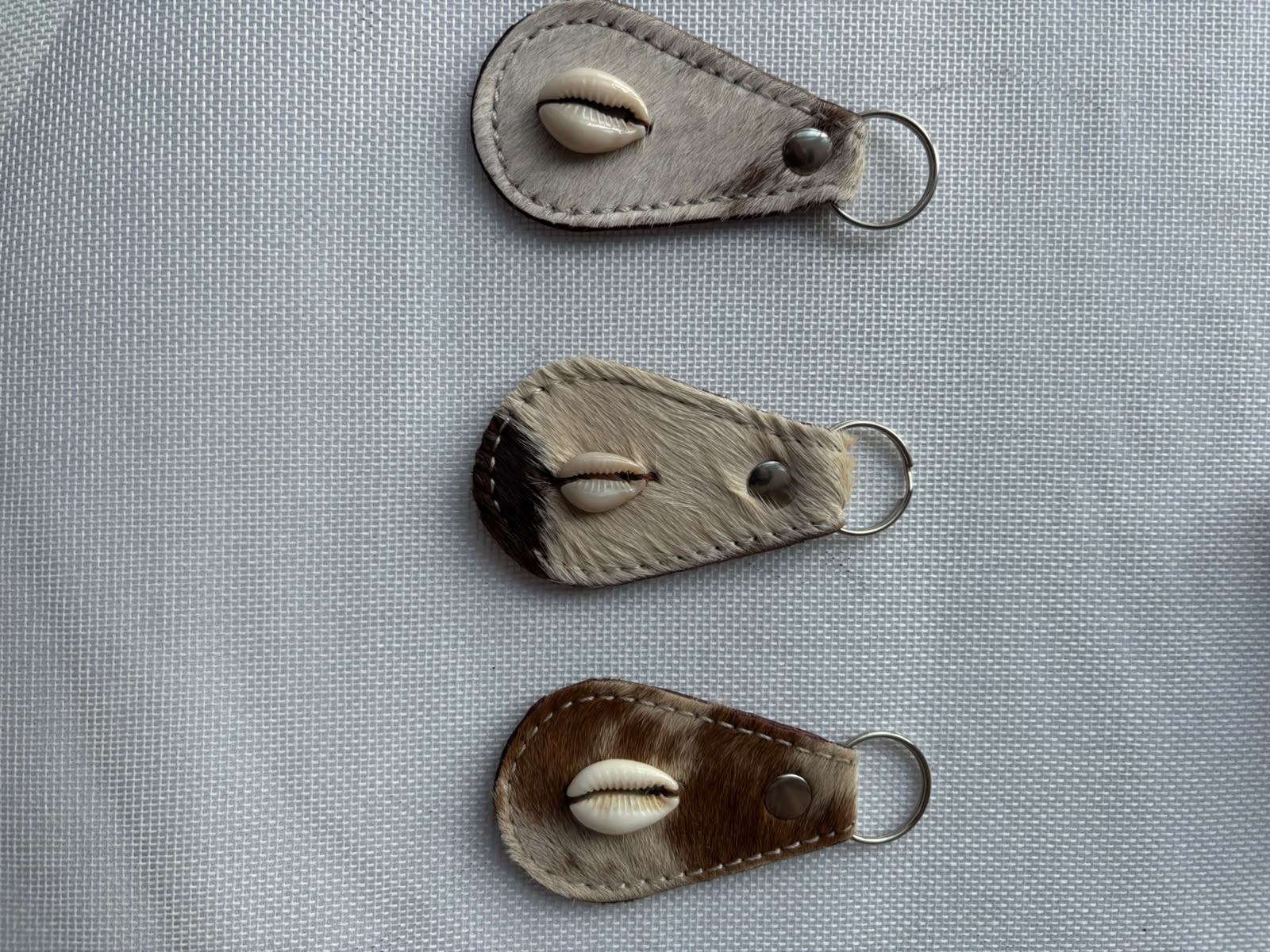 Carved Keychain — dark brown fur leather with cowrie shell close up