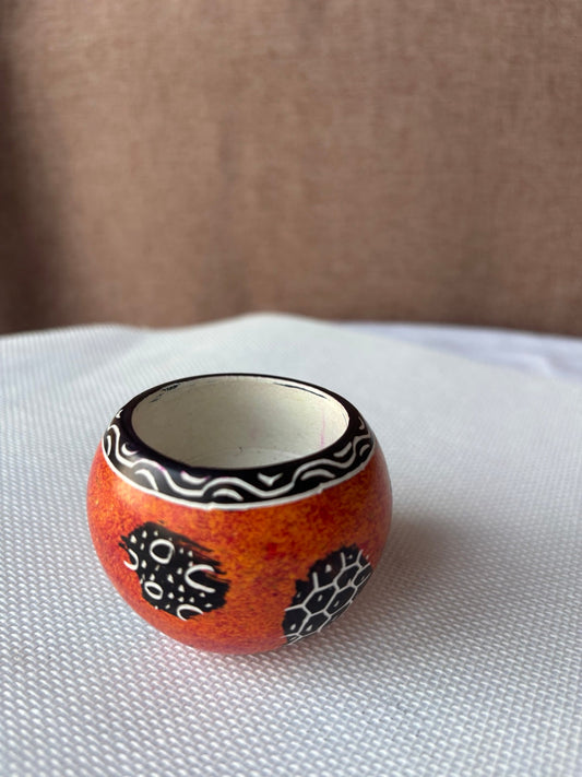 Hand-painted orange African candle pot with black and white motifs